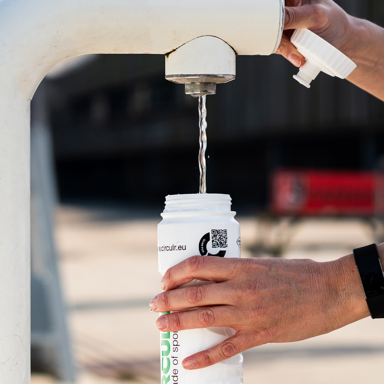 Een Eurobottle drinkfles wordt gevuld bij een tappunt; de QR-code op de fles verwijst naar het digitaal productpaspoort met informatie over herkomst en recycling.