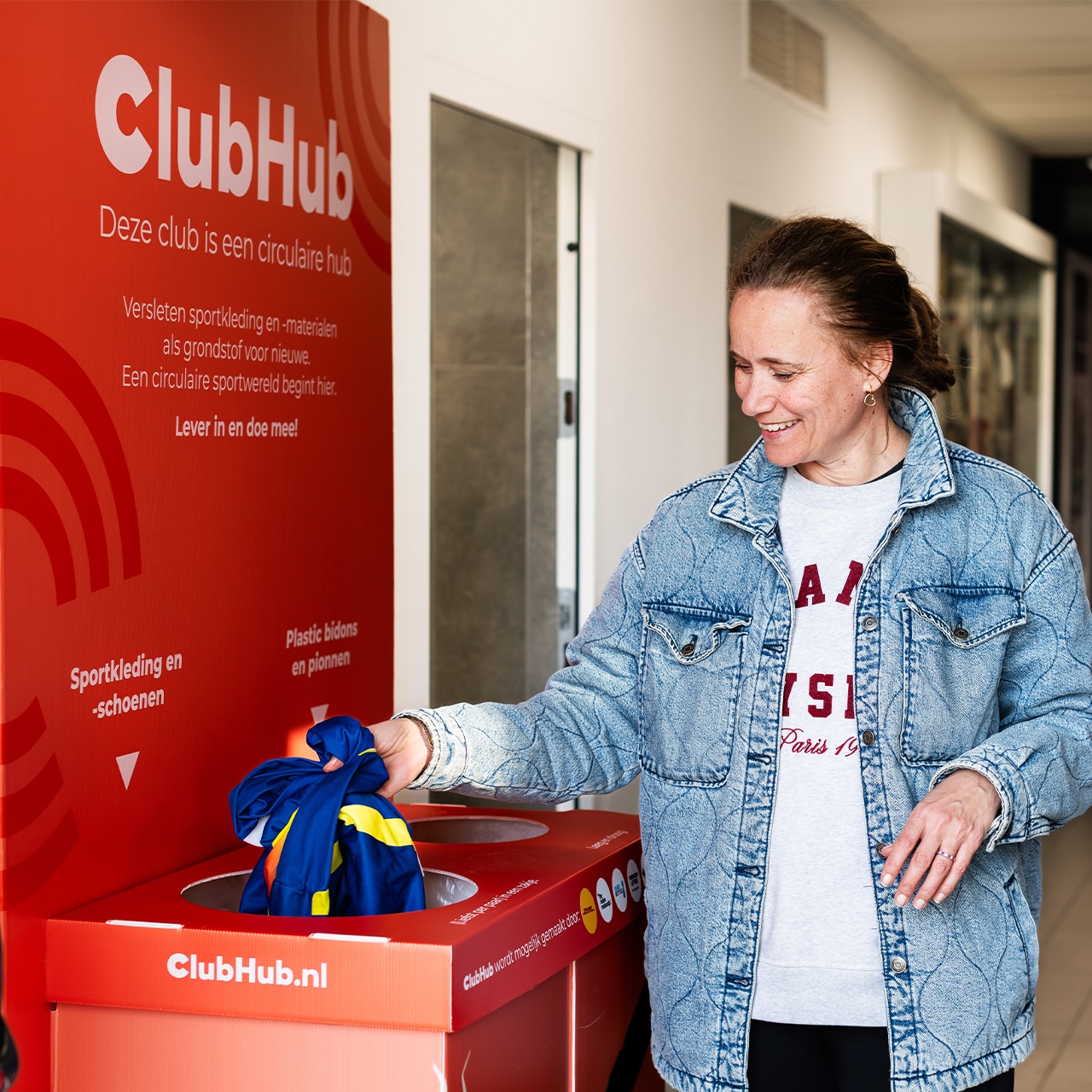 Een vrouw levert gebruikte sportkleding in bij een ClubHub-inzamelpunt – onderdeel van het circulaire netwerk dat ook plastic bidons inzamelt via QR-codes.