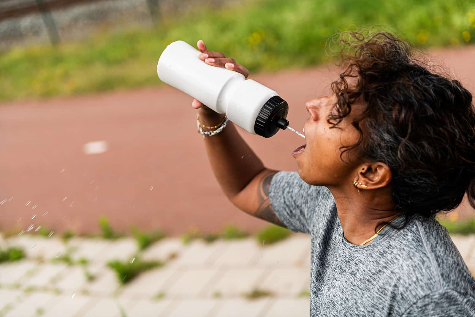 A girl squeezes a water bottle, and water comes out through the valve cap