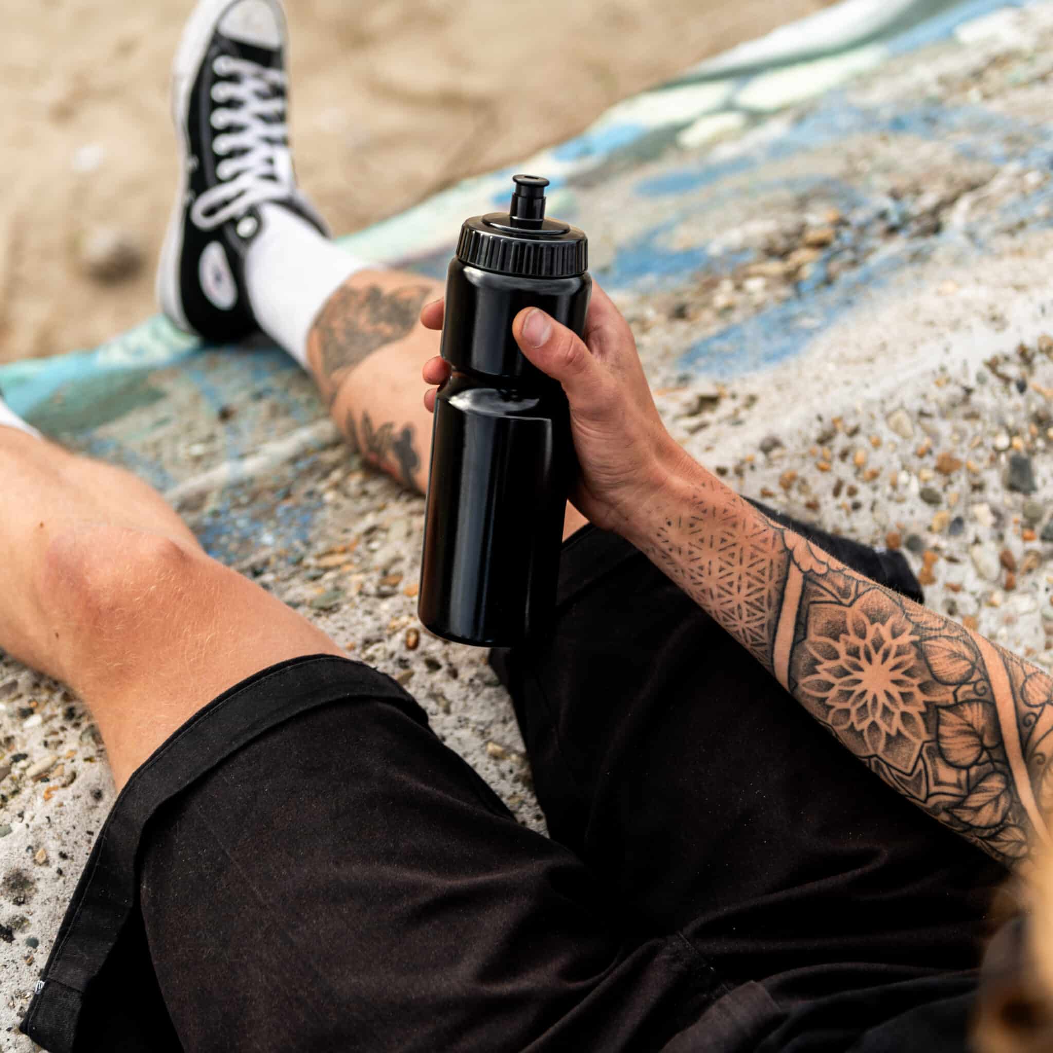 Ein Sportler hält während einer Pause eine schwarze Trinkflasche in der Hand.