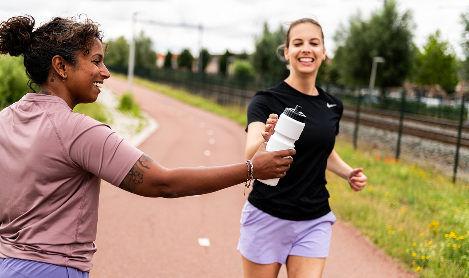 Witte Eurobottle-bidon met zwarte valve cap wordt doorgegeven aan een sporter.