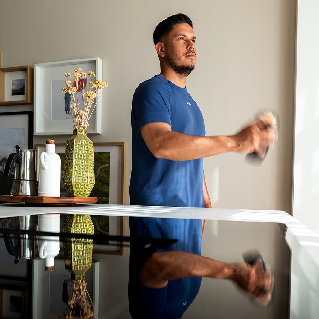 Man in een blauw sportshirt schudt een Eurobottle mesh-shaker om een eiwitshake te mengen