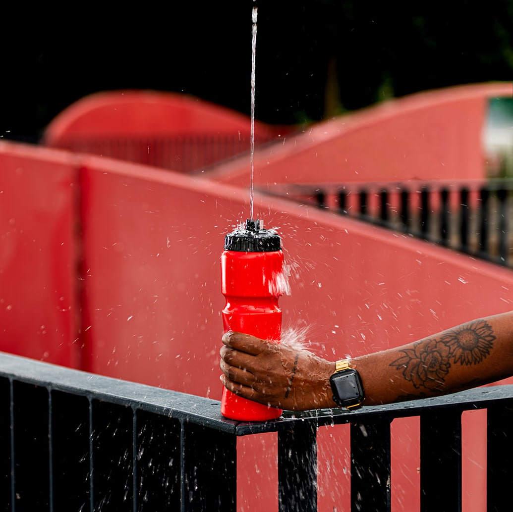 Water spuit omhoog uit de zwarte valve cap van een rode Eurobottle-bidon.