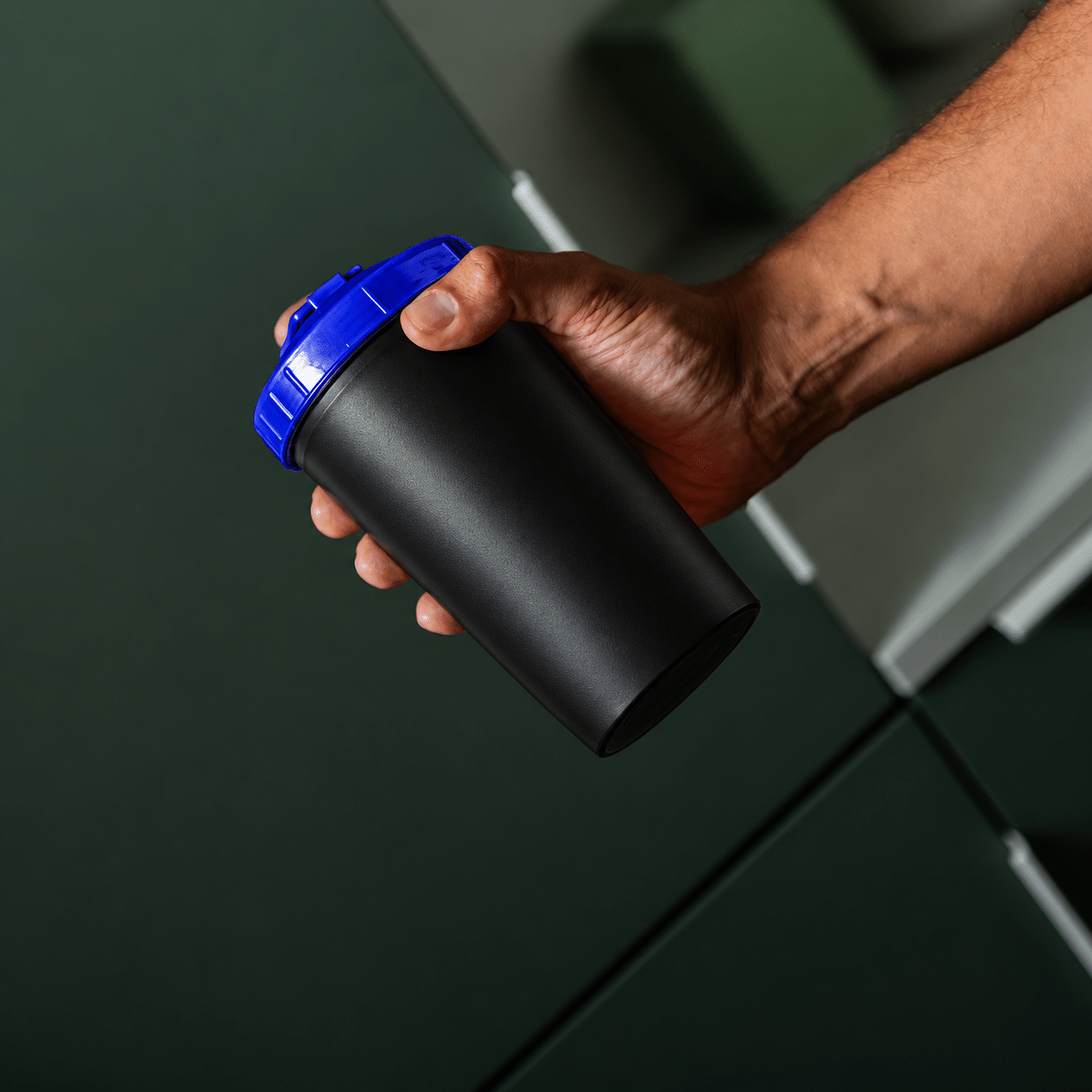 Zwarte Eurobottle shaker van 550 ml met koningsblauwe dop in de hand van een sporter